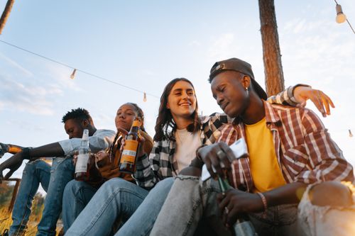 Free A diverse group of friends enjoying beverages outdoors during daytime with string lights overhead. Stock Photo