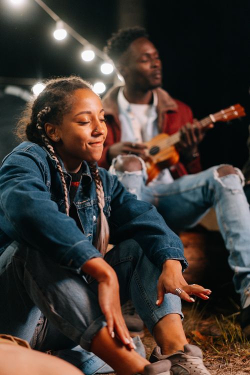 Free Two people enjoying a nighttime music session outdoors with guitar and campfire vibes. Stock Photo
