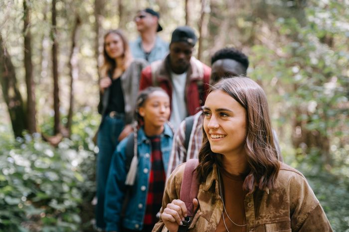 Five friends hiking together through a green forest, showing the shared activities that platonic relationship sites help people find