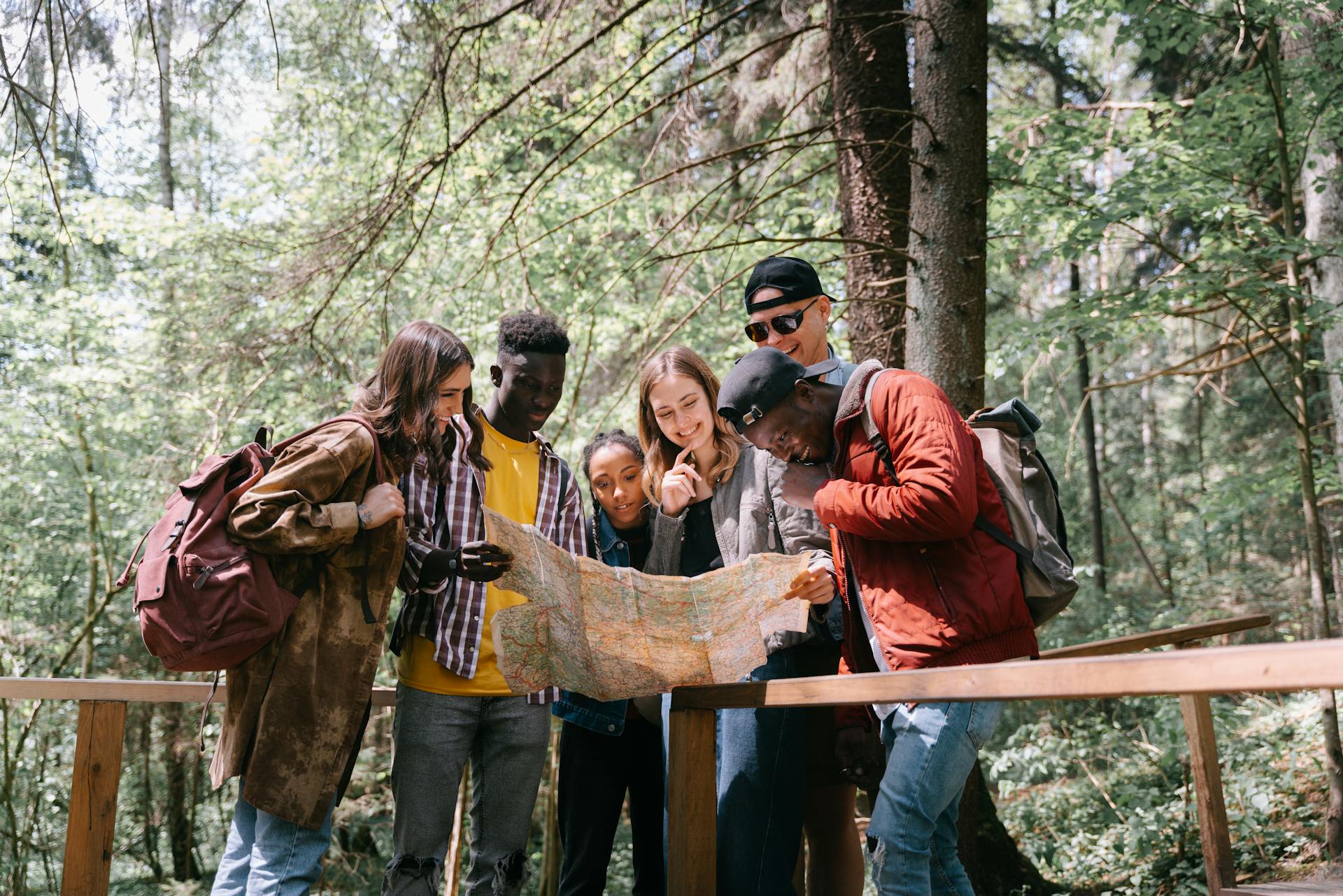 Group of diverse friends navigating a forest trail using a map. Perfect for adventure and travel themes.