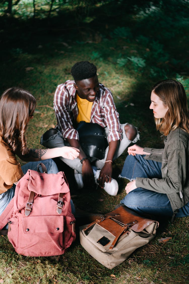 Backpackers Sitting On Green Grass 