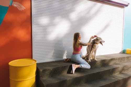 Woman Sitting on the Concrete Stairs Beside Her White Siberian Husky Dog 