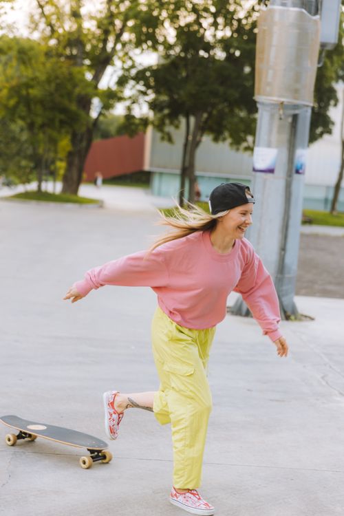 Free Young woman enjoying skateboarding in a vibrant city setting, wearing casual streetwear. Stock Photo