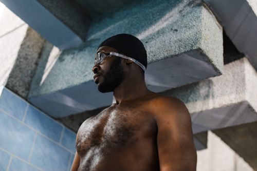 Free A confident male swimmer wearing a swim cap and goggles, captured indoors. Stock Photo