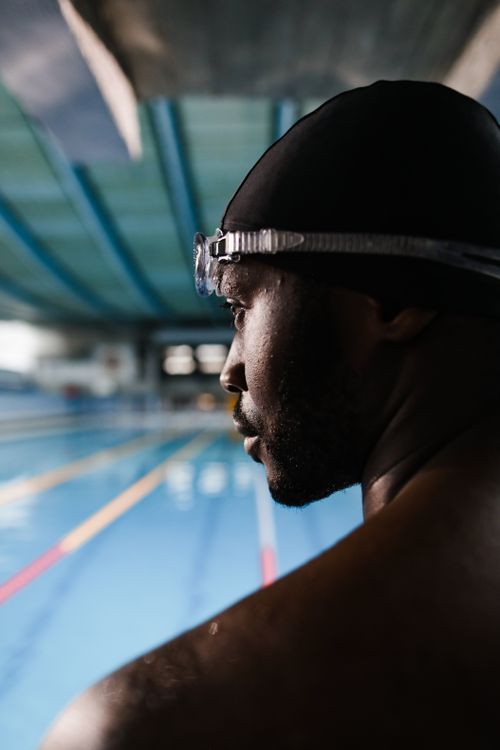 Free Athletic man with swimming gear focuses before a swim at an indoor pool. Perfect for sports and fitness themes. Stock Photo