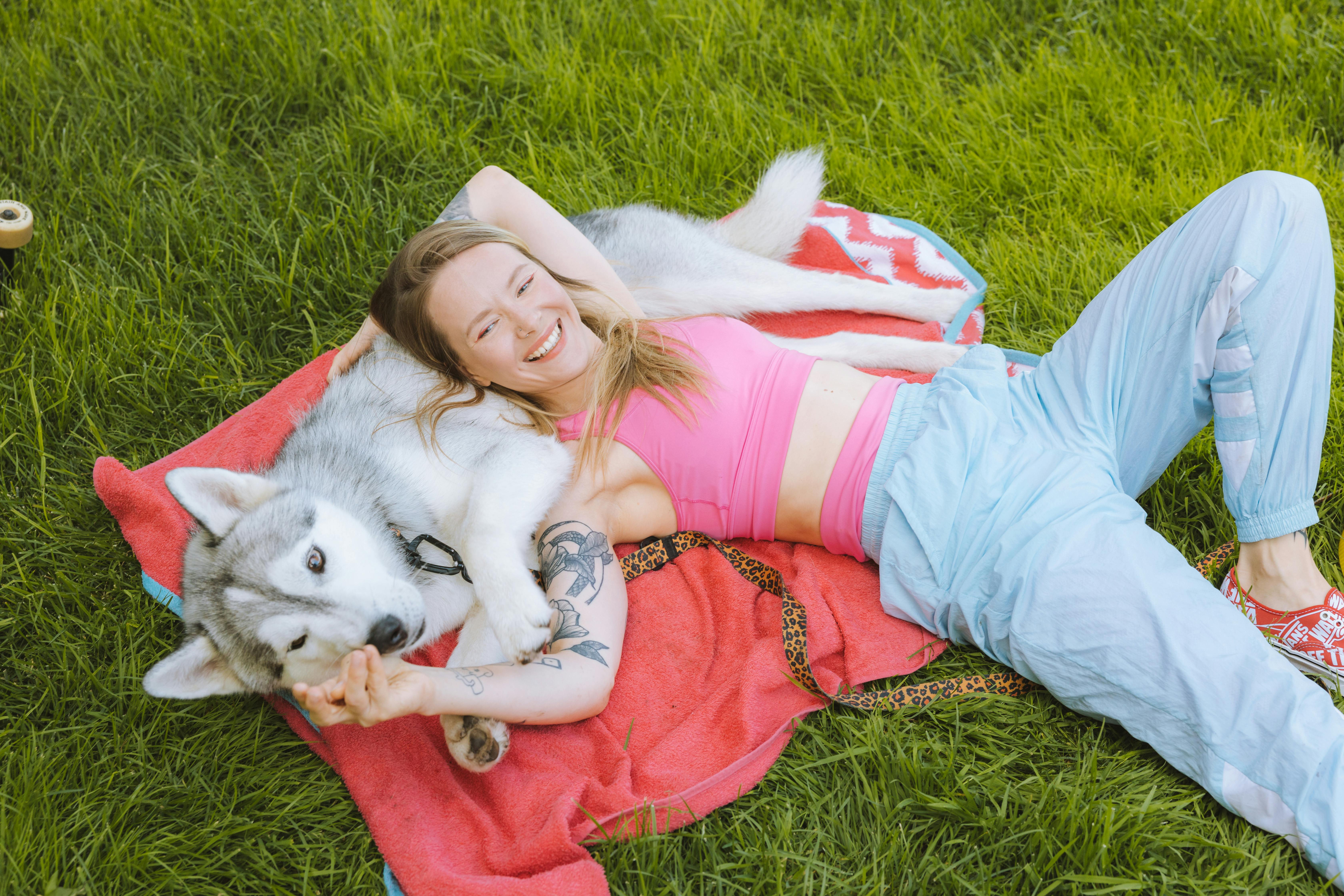 woman and dog lying on a blanket