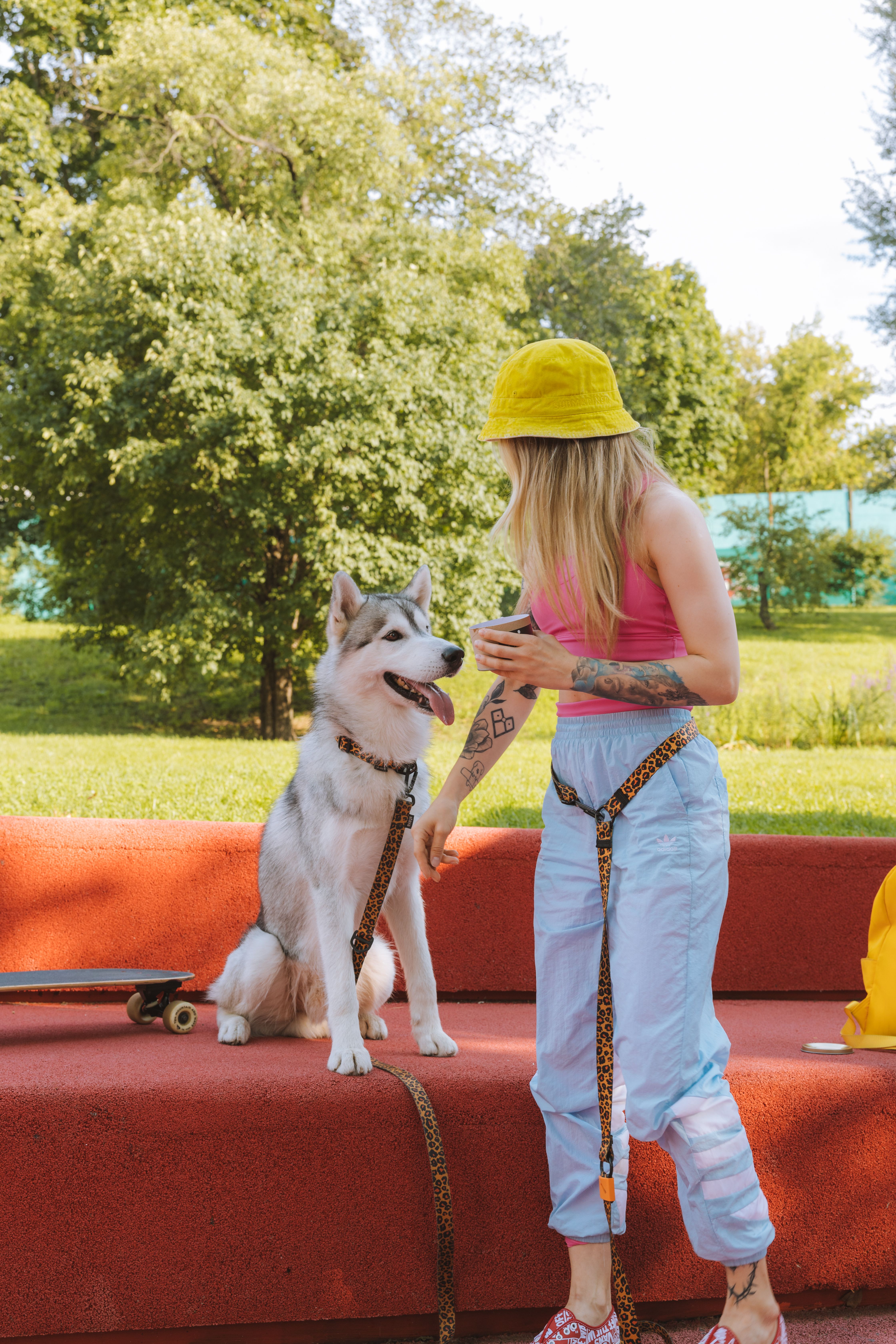 Young woman with a husky dog relaxing on a red park bench outdoors.