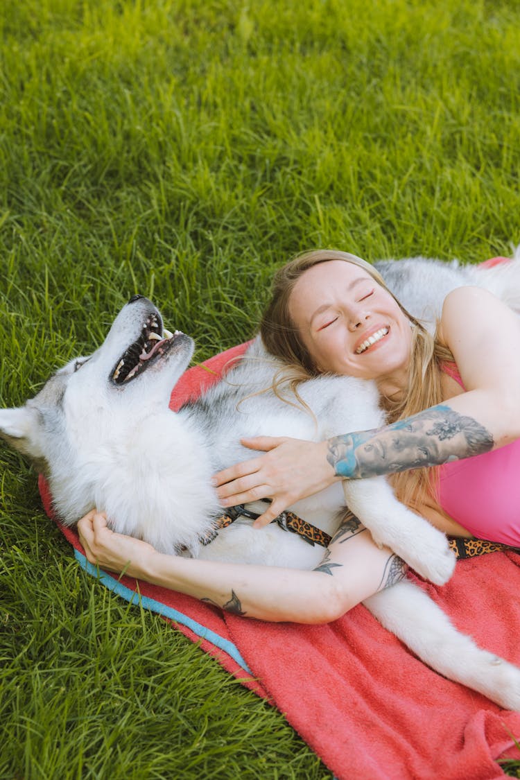 A Woman Lying On Grass With Her Dog