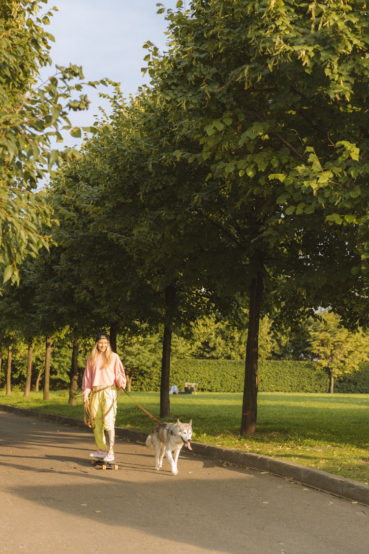 A Woman Walking In The Park With Her Dog