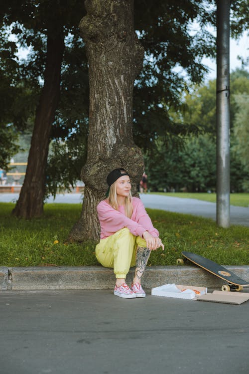 Woman in Pink Sweater Sitting on a Gutter