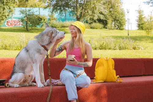 Woman Wearing Yellow Bucket Hat Touching the Dog's Face 
