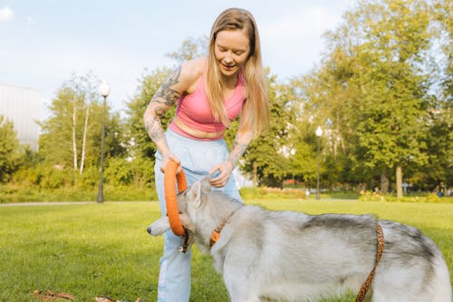 A Tattooed Woman Playing With Her Dog 