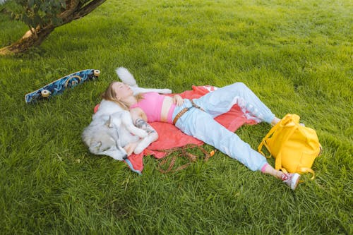 Free A Woman Resting with Her Dog on Grass Stock Photo