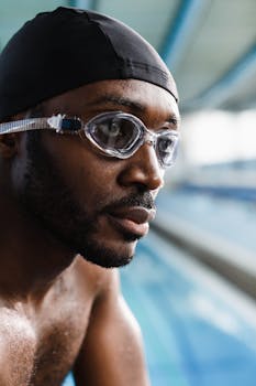 Portrait of an African American swimmer wearing goggles and swim cap indoors.