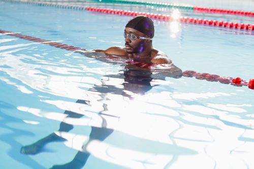 Free A focused swimmer wearing goggles and a swim cap in an indoor pool, perfecting his technique. Stock Photo