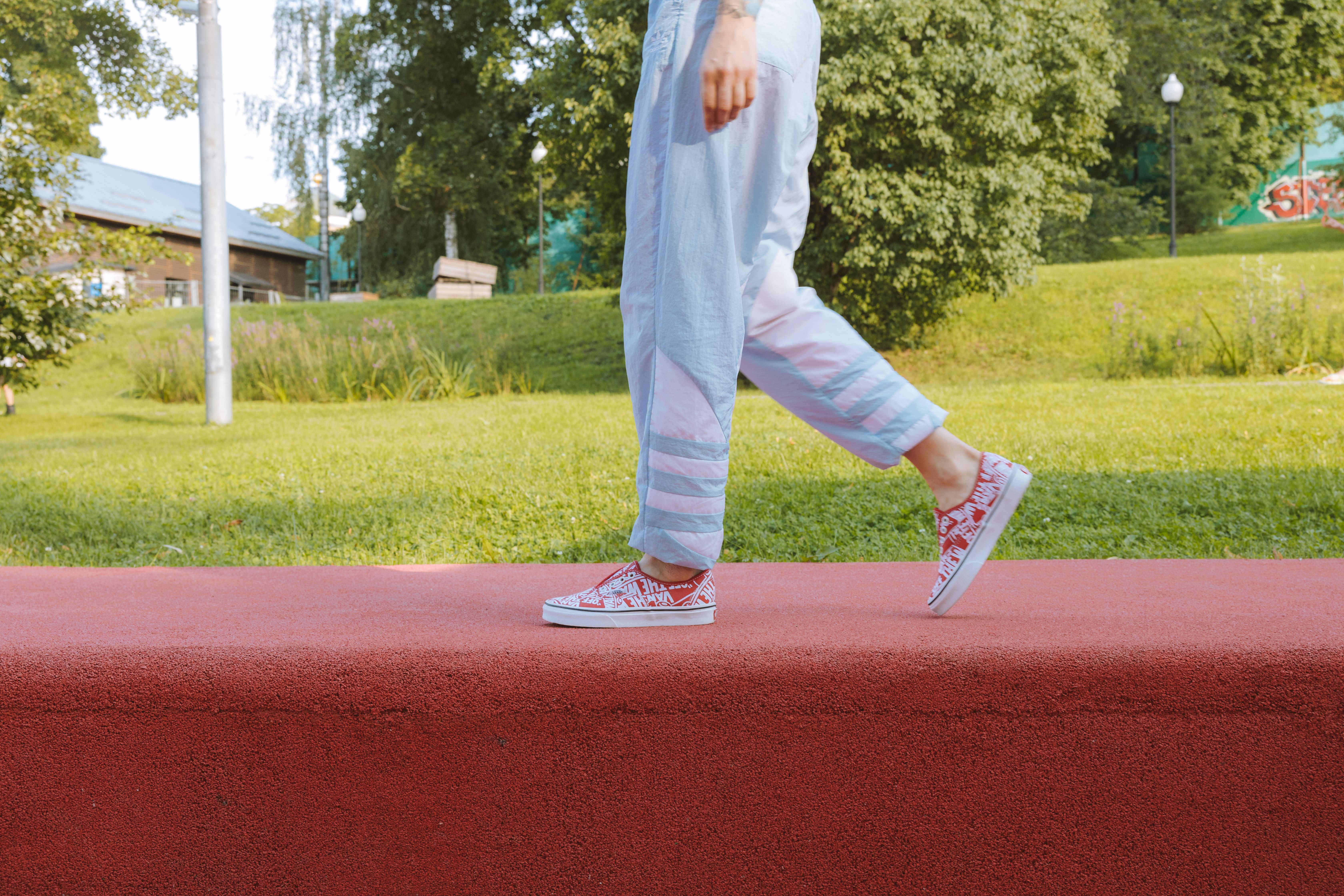 Casual scene of a young adult walking outdoors on a sunny day with colorful sneakers.