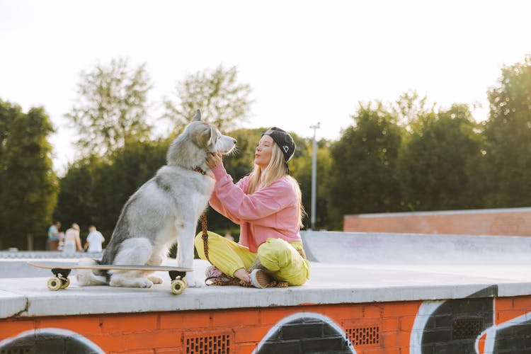 Woman Sitting On The Park Petting A Dog