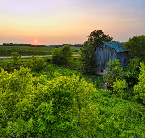 Brown Wooden House on the Green Grass Field during Sunset