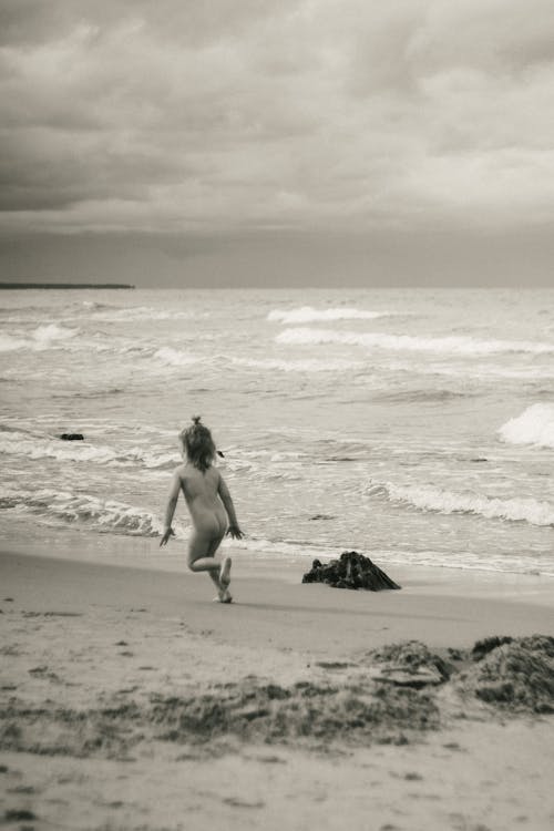 Grayscale Photo of a Kid Running at the Beach