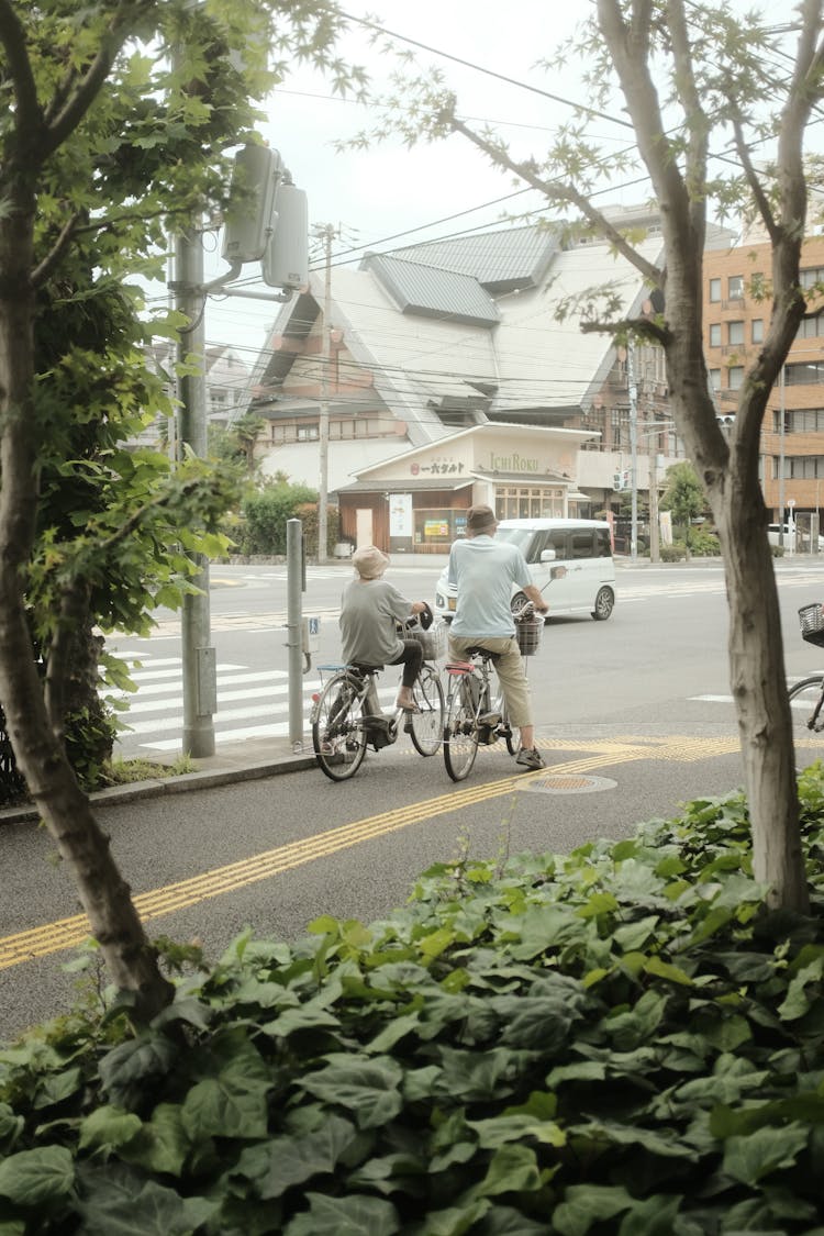 A Couple Riding Bicycles On A Concrete Road