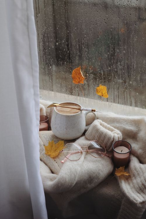 Free A warm, cozy autumn scene with coffee and candle by a rainy window. Stock Photo