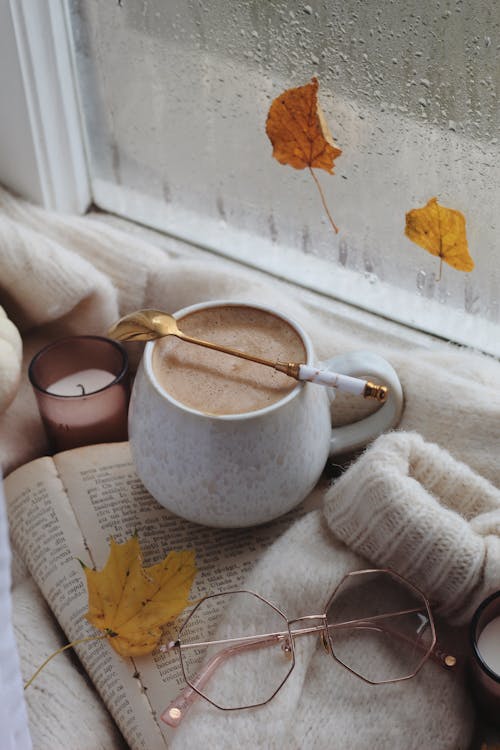 Coffee, eyeglasses and sweater on book in autumn scene