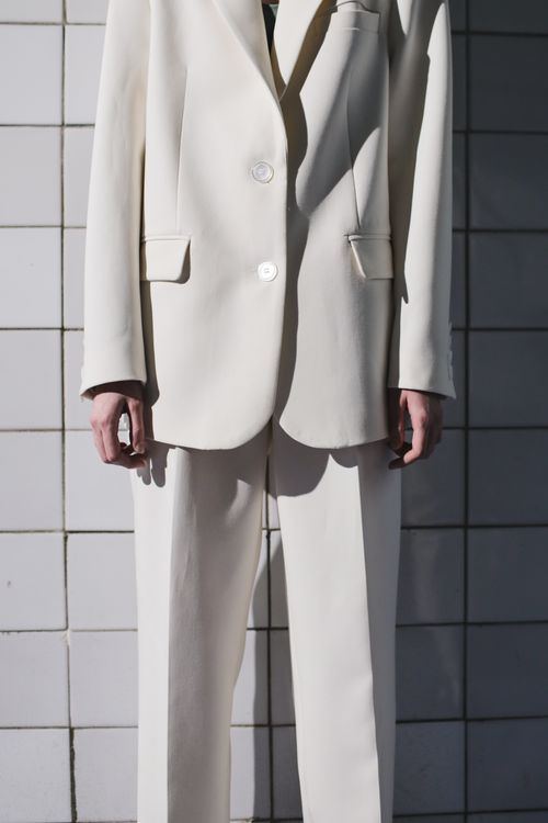 Free Elegant white suit fashion photography with a minimalist tiled backdrop, highlighting contemporary style. Stock Photo