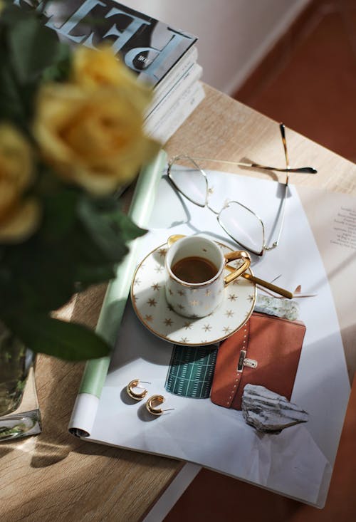 Teacup glasses and earrings laying on top of magazine