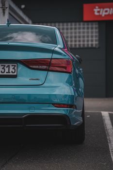 Close-up of a sleek, modern blue car parked on a city street, showcasing its luxurious rear design.