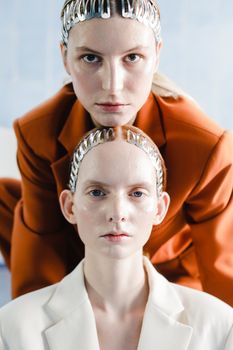 Contemporary portrait of two models with metallic hair accessories and stylish suits.