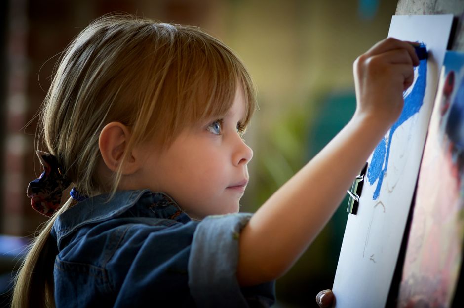 child drawing on large paper wall easel