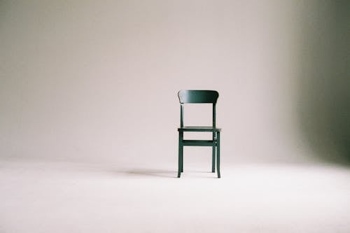 Зеленый деревянный стул на белой поверхности