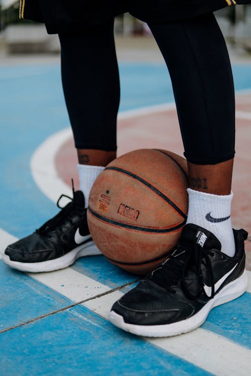 Person on basketball court holding ball between legs · Free Stock Photo