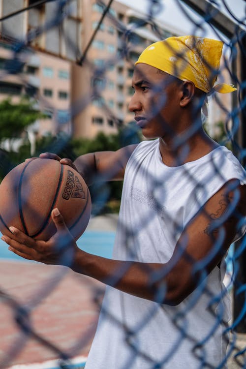Man holding basketball ball behind net