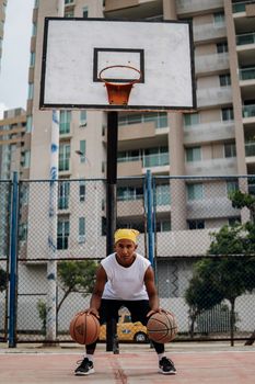 A young man dribbles basketballs on an outdoor court, showcasing skill and focus.