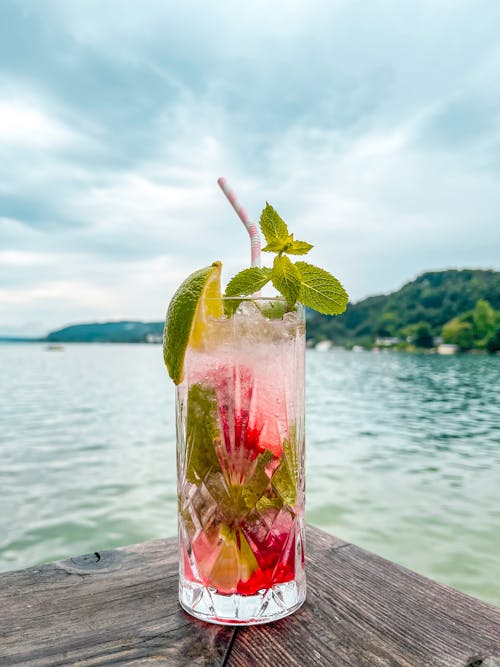 Clear Drinking Glass With Pink Liquid and Green Leaf on Brown Wooden Table