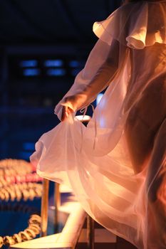 A graceful figure in a flowing lace dress stands by a pool, captured with warm lighting and a soft ambiance.