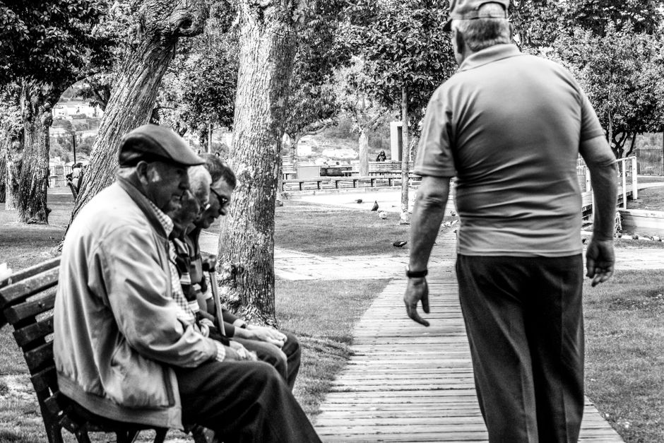 Una foto en blanco y negro espontánea de hombres mayores disfrutando de un momento tranquilo en un parque.
