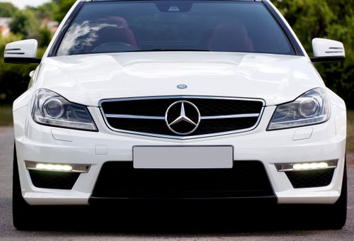 Free Close-up of a sleek, white luxury Mercedes-Benz C63 Coupe parked outdoors. Stock Photo