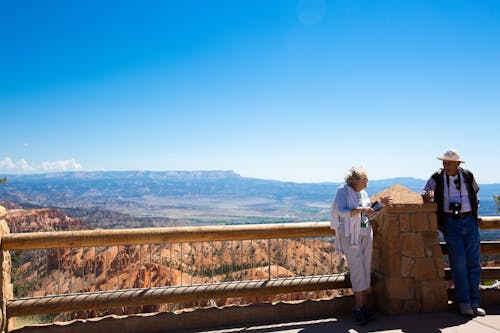 Tourists Standing by Barrier in Mountains