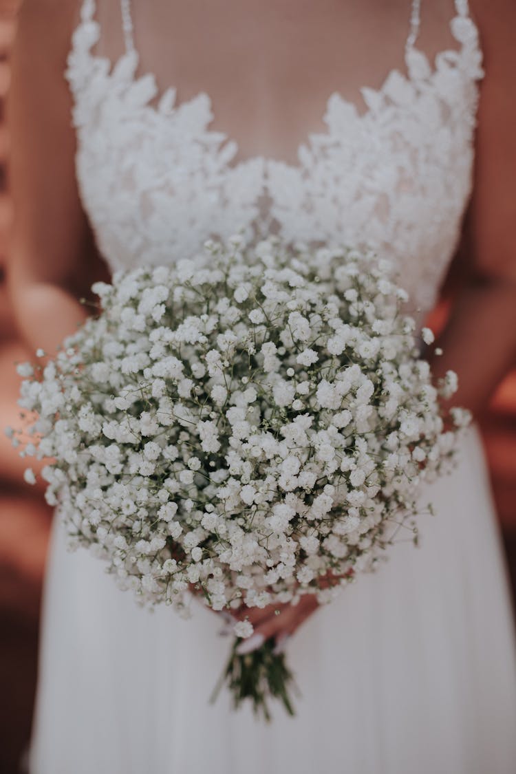 Bride Holding Bouquet Of Tiny White Flowers