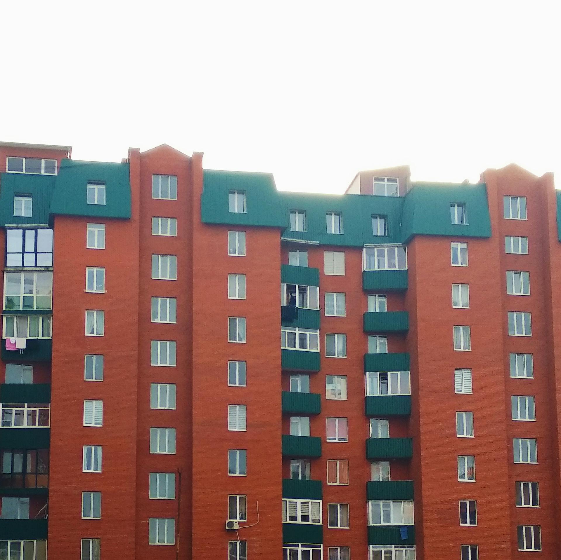 Exterior of modern multistorey apartment building with green roof and balconies on bright day