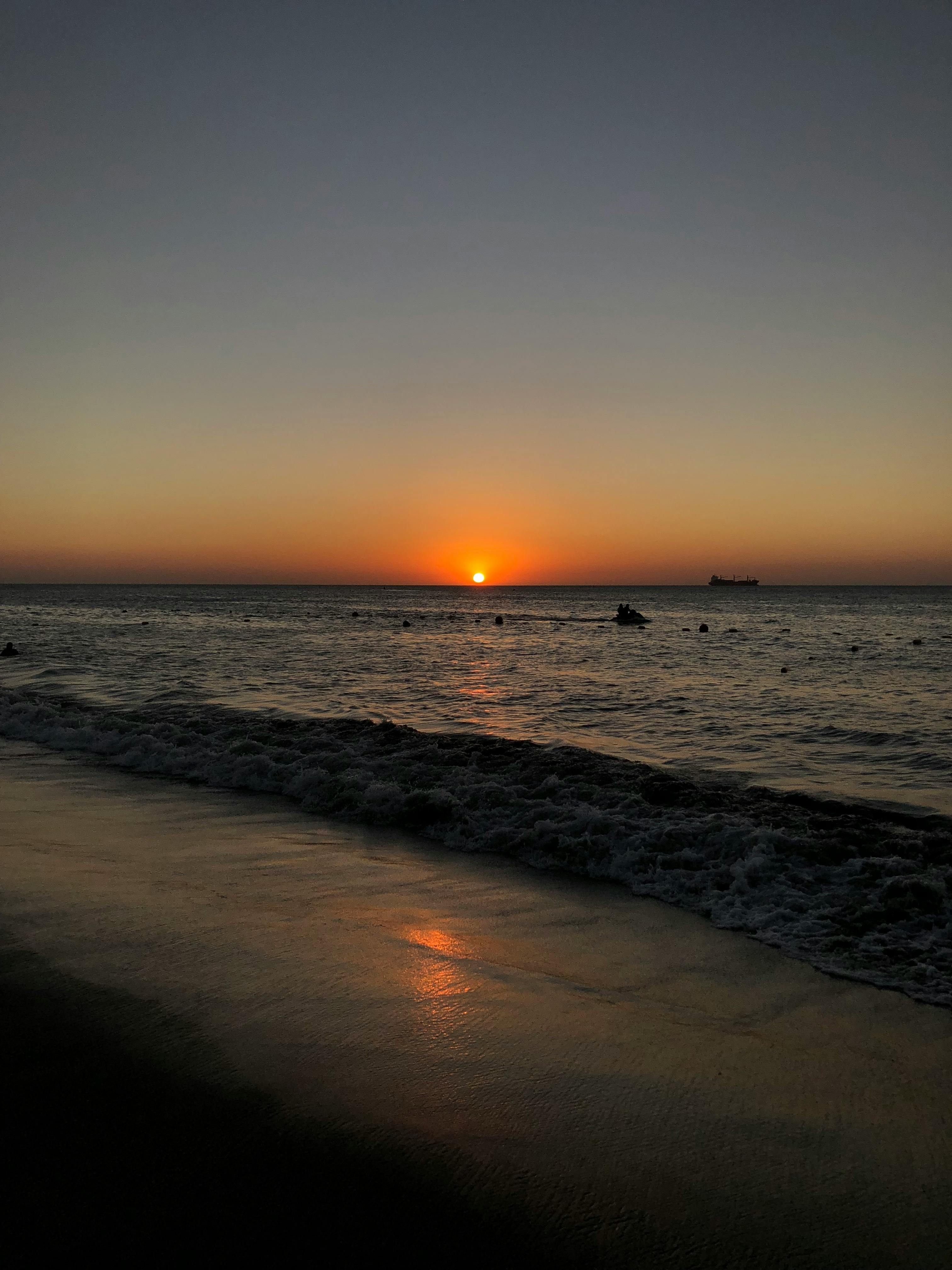 Beautiful sunset at Santa Marta beach, Colombia with serene waves and a silhouetted horizon.