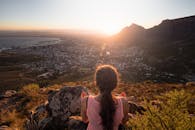 在开普敦的岩石山顶上，一名妇女正在欣赏令人惊叹的日出景色