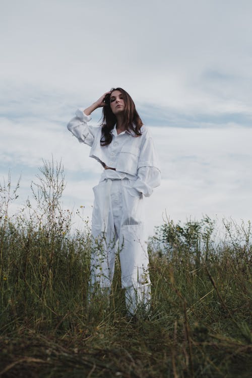 Photo of a Woman in White Clothes Standing on Grass