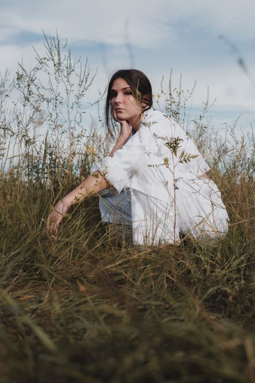 Woman in White Clothing Sitting on Green Grass Field · Free Stock Photo