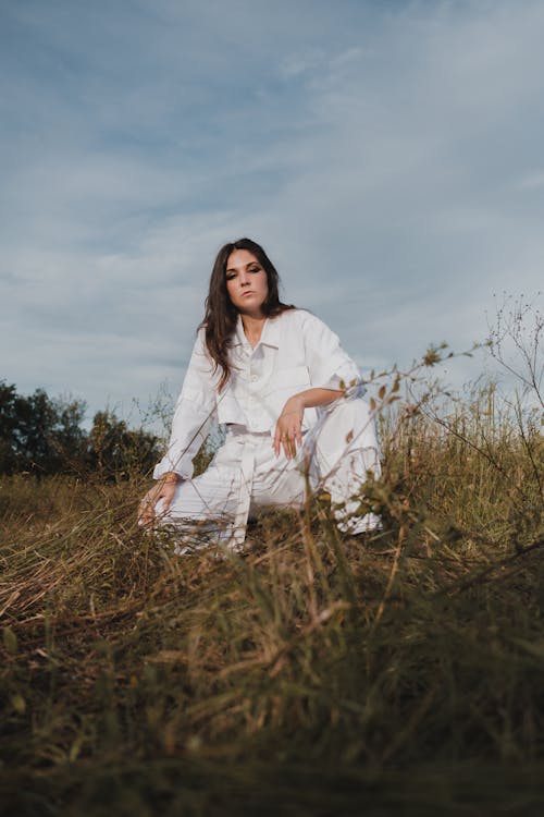 Woman in White Clothing Sitting on Brown Grass Field