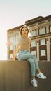 Woman in Blue Denim Jeans Sitting on Brown Concrete Bench