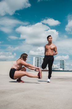 Two people stretching on a sunny rooftop in Orlando, focusing on fitness and health.