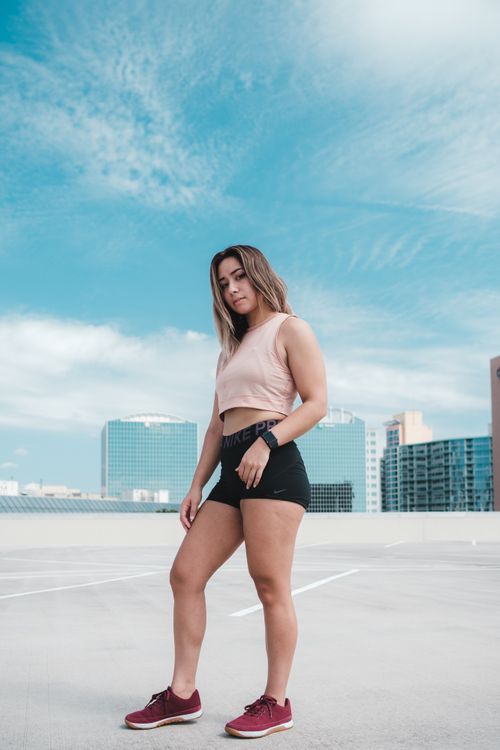 Free Athletic woman poses outdoors on a rooftop with city skyline in the background, embracing fitness and modern urban lifestyle. Stock Photo